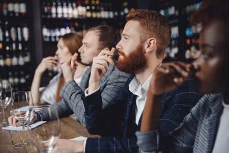 Young man listens to aroma of red wine at master class tasting in restaurant, training sommelierの写真素材