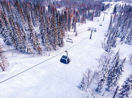 Winter mountains with ski lifts and snowy forest, aerial top viewの写真素材