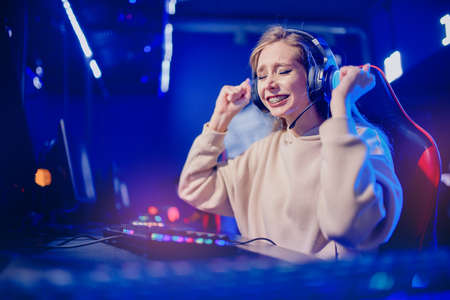 Young woman online video game tournament winner rejoices hand up, neon colorの写真素材