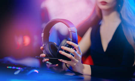Closeup hand of Woman hold headphones with microphone for video games and cyber sports on neon backgroundの写真素材