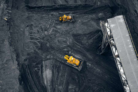 Two yellow excavators Loading coal handling anthracite in an open mine, aerial top viewの写真素材