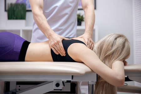 Doctor performs sports massage back neck therapy for young woman athlete after workout.の写真素材