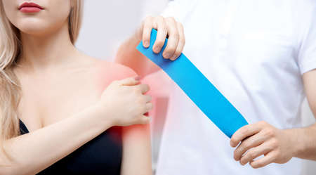 Kinesio therapy tape concept. Doctor physiotherapist conducts rehabilitation of sports injury of shoulder of woman athleteの写真素材