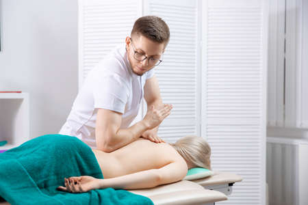 Concept physiotherapy massage for rehab sport injury athlete back. Doctor osteopath use therapy for woman in clinicの写真素材