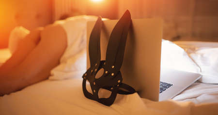 Concept online flirting, sex on Internet. BDSM leather mask background laptopの写真素材