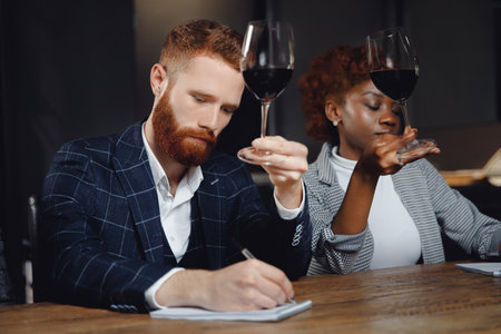 Sommeliers man and woman tasting red wine and making notes at degustation notepadの写真素材