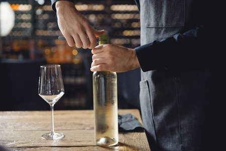 Sommelier opens cork of bottle of white wine with corkscrewの写真素材