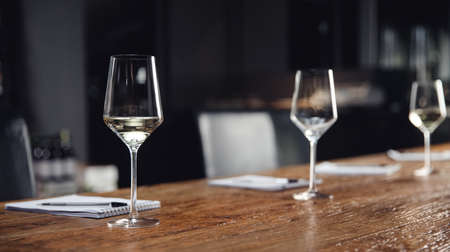 Banner Concept tasting white wine, row glasses with alcohol and notepad on table.の写真素材
