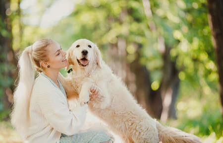 Concept Friendship girl and golden retriever. Pretty young woman with dog on background summer parkの写真素材