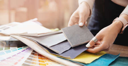Banner design interior. Young woman designer chooses set fabrics for curtains in textileの写真素材