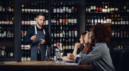 Master class for group of friends in restaurant, Sommelier talks about type of wineの写真素材