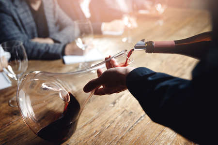 Sommelier and bartender training, Closeup hand of man pouring red wine from bottle into decanterの写真素材