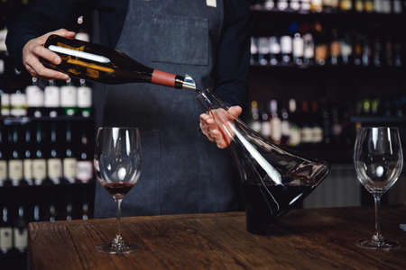 Sommelier pouring red wine into glass carafe decanter to make aeration drinkの写真素材