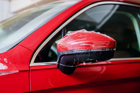 Closeup Installs vinyl film for protect paint body side mirrors red car.の写真素材