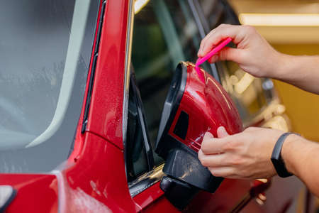 Master man installs vinyl film protect paint body side mirrors car.の写真素材
