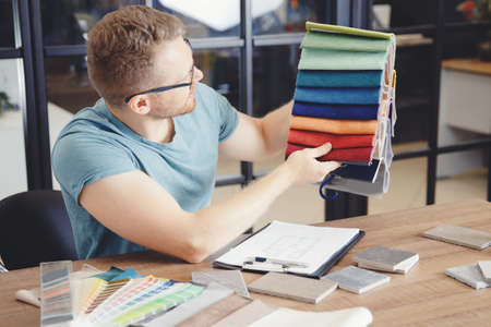 Author supervision of design project, male designer selects color of curtains and upholstery of upholstered furnitureの写真素材