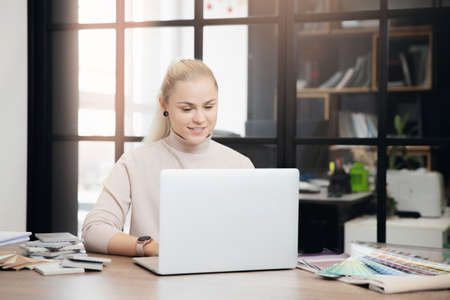Portrait young woman professional designer develops design of apartment project in workplace laptopの写真素材