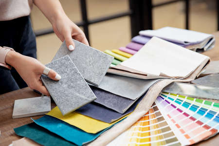 Hand of woman designer chooses ceramic tile and set fabrics for curtains in textile. Concept design interiorの写真素材