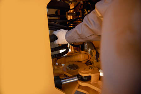 Professional mechanic checks hydraulic hose system equipment on excavator to raise bucketの写真素材