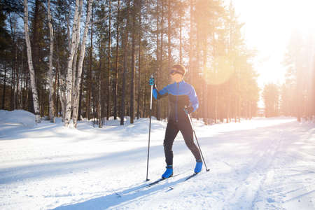 Cross country skiing, happy man skier active winter sport on snowy track, sunset backgroundの写真素材