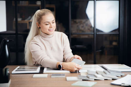 Young woman professional designer chooses ceramic tiles for apartment design project on workplaceの写真素材
