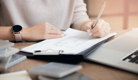 Architect draws plan of partitions of apartment, interior designer young woman works at laptop workplaceの写真素材