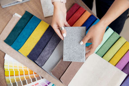 Concept design interior. Top view hand of woman designer chooses set fabrics for curtains in textileの写真素材