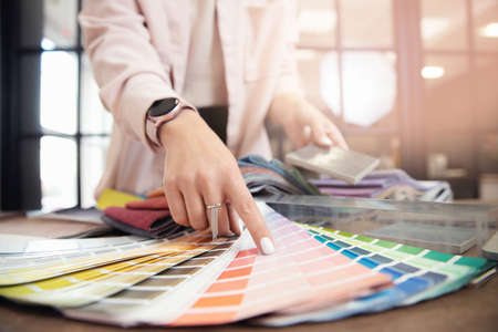 Closeup hand of woman decorator, interior and graphic designer, architect is choosing catalogue colors ral for web projectの写真素材