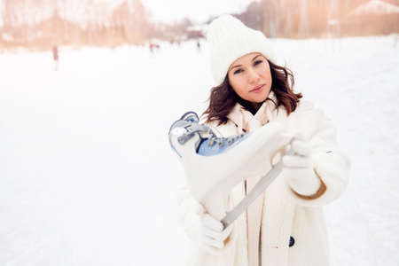 Happy smile woman in winter with skates on outdoors ice rink sunsetの写真素材
