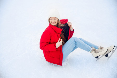 Happy smile woman in white hat and red coat in winter with skates on ice rink, top viewの写真素材