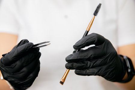 Master holds tweezers and eyebrow grooming comb for womenの写真素材