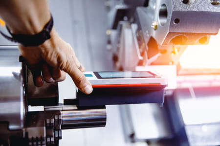 Industrial worker measures roughness and frequency of machined part after lathe with instrumentの写真素材