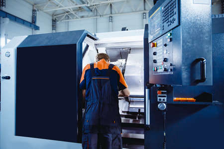 Young male engineer operating CNC machinery in iron metal factoryの写真素材