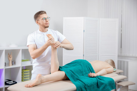 Concept sports massage for woman. Osteopath therapist working with legs muscle athlete after workoutの写真素材