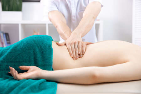 Medical massage of back young woman, closeup of hands of male doctor osteopathの写真素材
