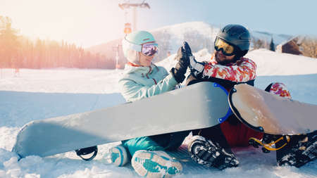 Smiling couple woman and man with snowboards background snowy mountain ski resort, sunny day sunlight. Concept travel winter sportsの写真素材