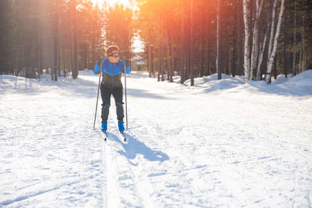 Cross country skiing, happy man skier active winter sport on snowy track, sunset backgroundの写真素材