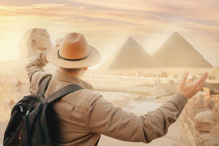 Travel man in hat background pyramid of Egyptian Giza and Sphinx, sunset Cairo, Egyptの写真素材
