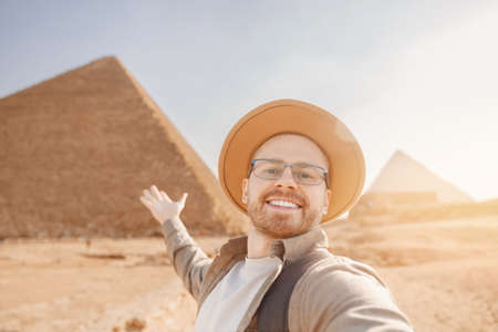 Happy tourist man in hat take selfie photo background pyramid of Egyptian Giza sunset, Cairo, Egyptの写真素材