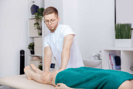 Therapist osteopathy working sports massage with legs of woman athleteの写真素材