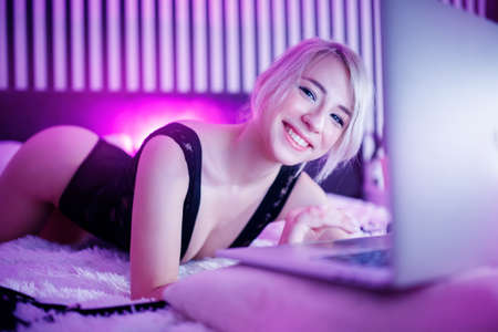 Adult happy beautiful woman working on as online webcam model. Concept virtual sex for fansの写真素材