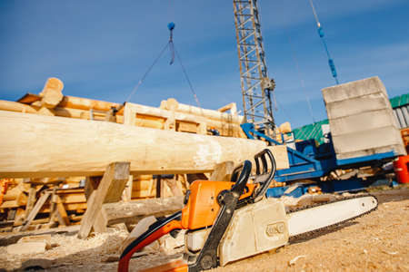 Concept of construction of wooden houses from solid logs, close-up chainsawの写真素材