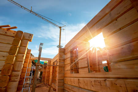 New house wooden log construction interior with exposed framing roof with sun lightの写真素材