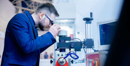 Industrial worker use microscope for precision plasma welding at modern factory floorの写真素材