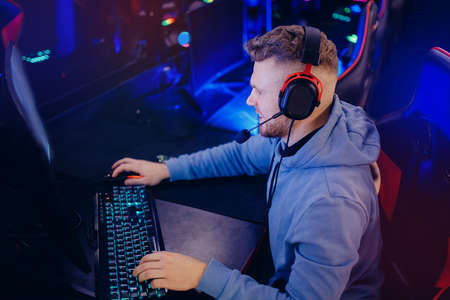 Streamer Young man plays computer games in headphones, neon lights. Concept game club for trainingの写真素材