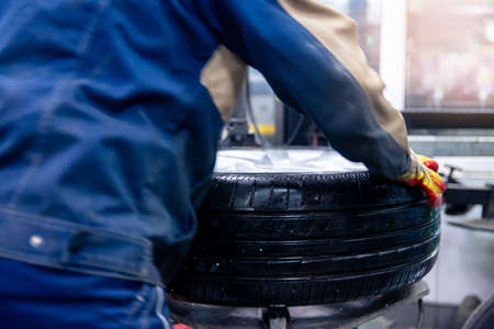 Concept car service replacement of winter and summer tires. Mechanic holding wheels at garageの写真素材