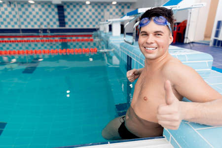 Young man swimmer showing good thumb sign in pool, swimming competition conceptの写真素材