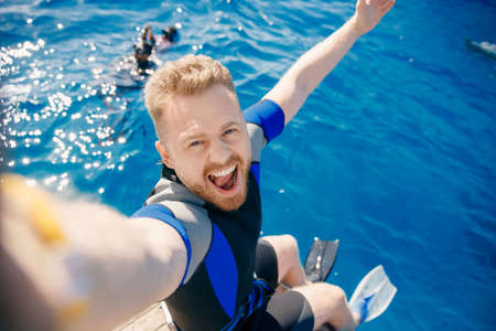 Selfie tourist man in flippers and wetsuit diver to dive into sea on boat. Concept diving trip Egypt ocean swimの写真素材