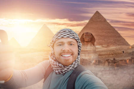 Travel Selfie photo man in hat background pyramid of Egyptian Giza and Sphinx, sunset Cairo, Egypの写真素材