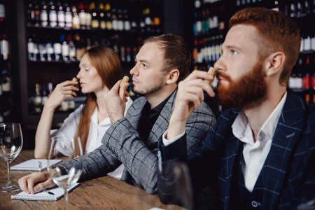 Young man listens to aroma of red wine at master class tasting in restaurant, training sommelierの写真素材